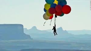 Illusionist flies holding onto helium balloons